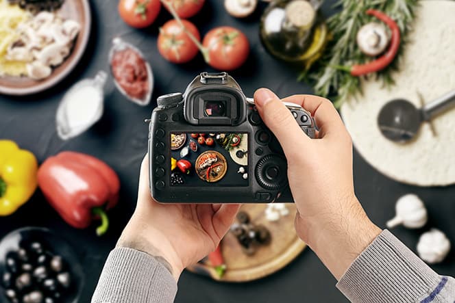 photographe qui fait une photo culinaire avec son appareil photo reflex numérique