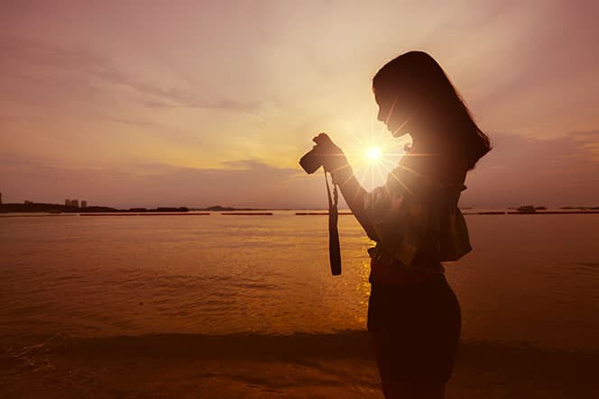 femme avec son appareil photo au coucher du soleil